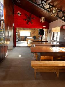 a restaurant with wooden tables and a living room at Refugio Pehuenche in Los Molles