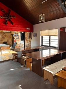 a room with tables and benches and a fireplace at Refugio Pehuenche in Los Molles