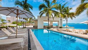 a swimming pool with chairs and umbrellas next to the ocean at Gorgeous 1BR Condo with Pools & Sea Views in Puerto Vallarta