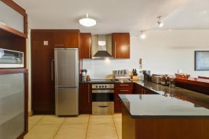 a kitchen with wooden cabinets and stainless steel appliances at Luxury Ocean View 1203 with Workspace, AC & Beachfront Location in Cape Town