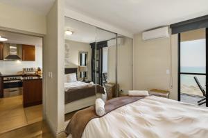 a bedroom with a large bed and a bathroom at Luxury Ocean View 1203 with Workspace, AC & Beachfront Location in Cape Town
