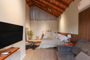 a living room with a bed and a flat screen tv at Pousada Calza - Vale dos Vinhedos - Bento Gonçalves in Bento Gonçalves