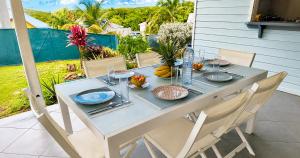 a table with plates and utensils on a patio at Villa Arc-en-ciel in Le Moule