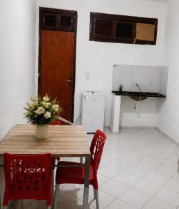 a kitchen with a table and two red chairs at Pousada Quixadá Central in Quixadá