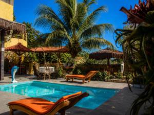 a swimming pool with chairs and a palm tree at Pousada Mirante Pôr do Sol in Maricá