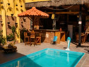 a swimming pool in front of a house with an umbrella at Pousada Mirante Pôr do Sol in Maricá