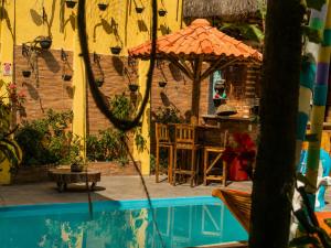 a patio with a table and an umbrella next to a pool at Pousada Mirante Pôr do Sol in Maricá