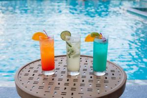 three cocktails sitting on a table next to a swimming pool at Best Western Orlando Gateway Hotel in Orlando