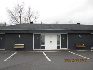a black building with two benches in a parking lot at Motel Parc Beaumont Inc. in Beaumont