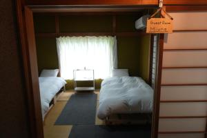two beds in a room with a sign that reads guest room mine at COSMOS Iya Valley in Akano
