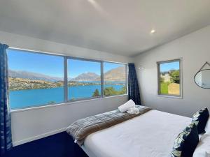 a bedroom with a large window with a view of the water at Epic Views and Deck | Spacious Queenstown Home in Queenstown