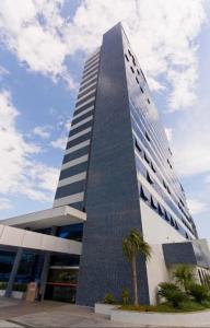 a tall building with a palm tree in front of it at Intercity - Apartmento 412 in Manaus