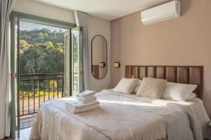 a bedroom with a large bed with a balcony at Pousada Calza - Vale dos Vinhedos - Bento Gonçalves in Bento Gonçalves