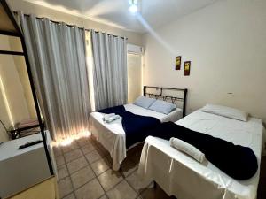 a bedroom with two beds and a window at Pousada Requinte in Vila Velha