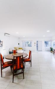 a dining room with tables and chairs and a living room at Casa Las Dunas in Monte Hermoso