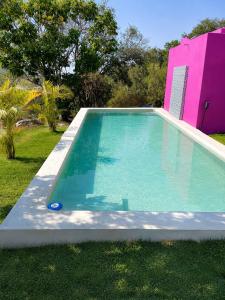 a swimming pool in a yard with a pink building at Romantic Dome & French Cuisine in Jantetelco