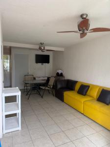 a living room with a yellow couch and a table at Casa privada, alberca, jacuzzi y asador Teques in Jojutla