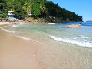 a sandy beach with waves coming in from the ocean at Aconchego Ebenézer in Praia de Provetá 