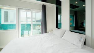 a white bed in a room with a window at Geoje Wave Hotel & Pension in Geoje +5 photos