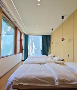 three beds in a room with a large window at Tiger Leaping Half Way Guest House in Longpan