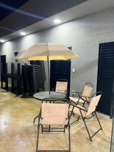 a table with chairs and an umbrella in a room at Casa de hospedagem e lazer in Sao Jose do Rio Preto