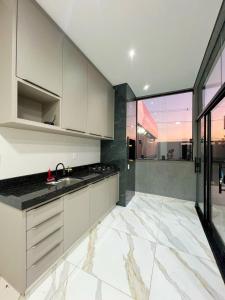a kitchen with white cabinets and black counter tops at Casa de hospedagem e lazer in Sao Jose do Rio Preto