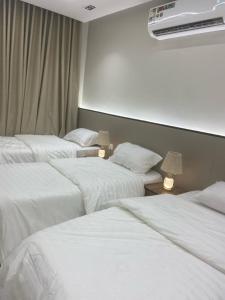 a hotel room with three beds with white sheets at فندق ميراب الروضة in Al Khansāk
