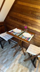 a wooden table with two chairs and a table with glasses at Chalé Rancho Ouro Verde in Rolândia
