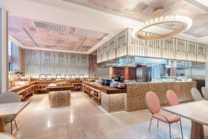 a restaurant with tables and chairs and a kitchen at Mercure Urumqi Doowin Wanda Plaza in Ürümqi +24 photos