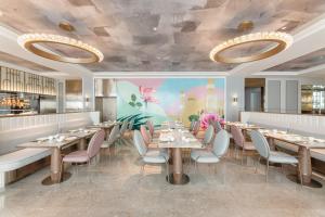 a dining room with tables and chairs and a mural at Mercure Urumqi Doowin Wanda Plaza in Ürümqi