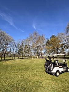 a golf cart parked in a field of grass at Les sarrays Golf et Lodges in Neuvy-Pailloux