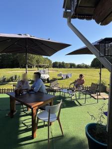 two people sitting at a table under an umbrella at Les sarrays Golf et Lodges in Neuvy-Pailloux