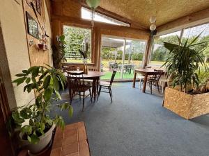 a dining room with tables and chairs and plants at Les sarrays Golf et Lodges in Neuvy-Pailloux