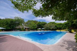 a large blue swimming pool with trees in the background at Deluxe Studio-Condo at Tambuli Seaside Living in Maribago