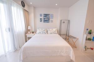 a white bedroom with a large bed with white sheets at Deluxe Studio-Condo at Tambuli Seaside Living in Maribago +25 photos