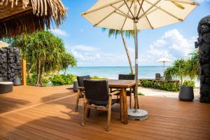 a wooden deck with a table and an umbrella at Aitutaki Escape Resort & Spa in Arutanga
