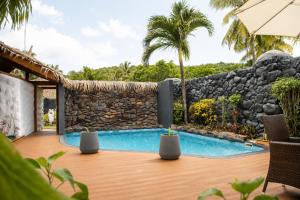 an outdoor deck with a swimming pool and a stone wall at Aitutaki Escape Resort & Spa in Arutanga