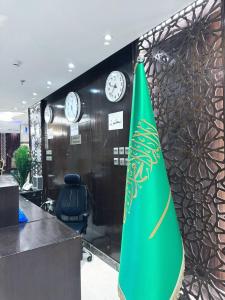a green umbrella in an office with clocks on a wall at فندق ميراب الروضة in Al Khansāk