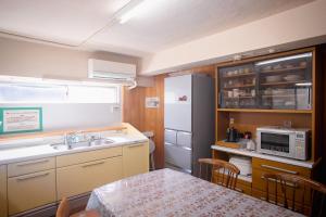 a small kitchen with a sink and a refrigerator at 網代温泉源泉かけ流し 阿治古の宿 in Atami