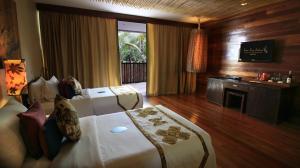a hotel room with two beds and a television at Kupu Kupu Jimbaran Beach Club & Spa in Jimbaran