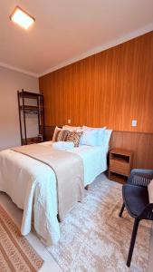 a bedroom with a large bed and a chair at Suíte Ipê-Amarelo in Camanducaia
