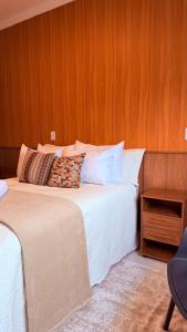 a bedroom with two beds and a wooden wall at Suíte Ipê-Amarelo in Camanducaia +4 photos