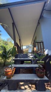 a porch with two potted plants and a picnic table at The Canal Hut Chaloklum in Chaloklum