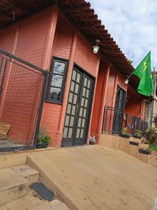 a red brick house with a green flag on it at Suíte aconchego in Domingos Martins