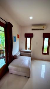 a room with a bed and a couch and windows at The Canal Hut Chaloklum in Chaloklum