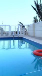 a swimming pool with blue water and a white fence at استراحة الروابي in Salalah +5 photos