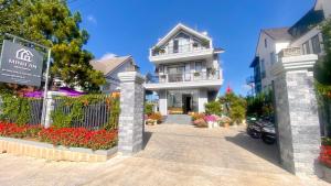 a white house with a gate and flowers in front of it at Minh An Villa in Da Thanh