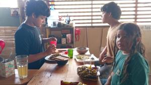 a group of people sitting at a table eating food at dondelachatahostel in Máncora