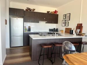 a kitchen with a counter with stools and a refrigerator at Jasper 3 in Jindabyne