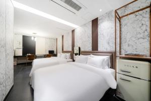 a hotel room with three white beds in it at Yeoksam Lumiere Hotel in Seoul
